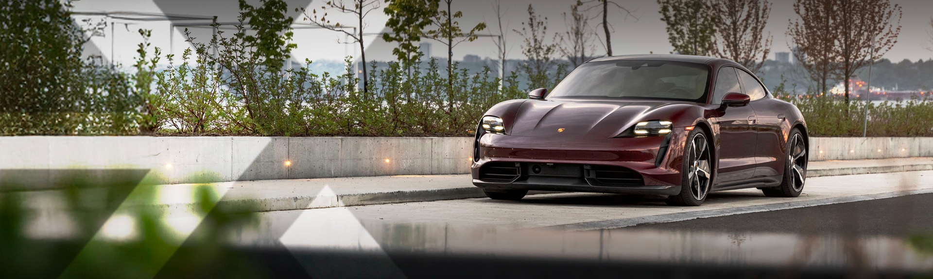 nexauto : Porsche Taycan d'occasion rouge devant le Fleuve Saint-Laurent.