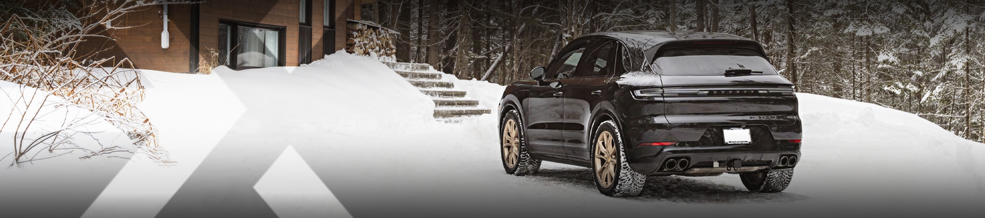 nexauto : Porsche Cayenne d'occasion noir dans la neige avec un décor de forêt en arrière.